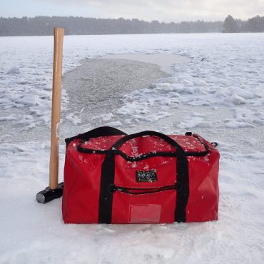 Image shows a red Montrose Bag on ice, with a hammer for outdoor swimming.