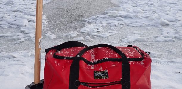 Image shows a red Montrose Bag on ice, with a hammer for outdoor swimming.